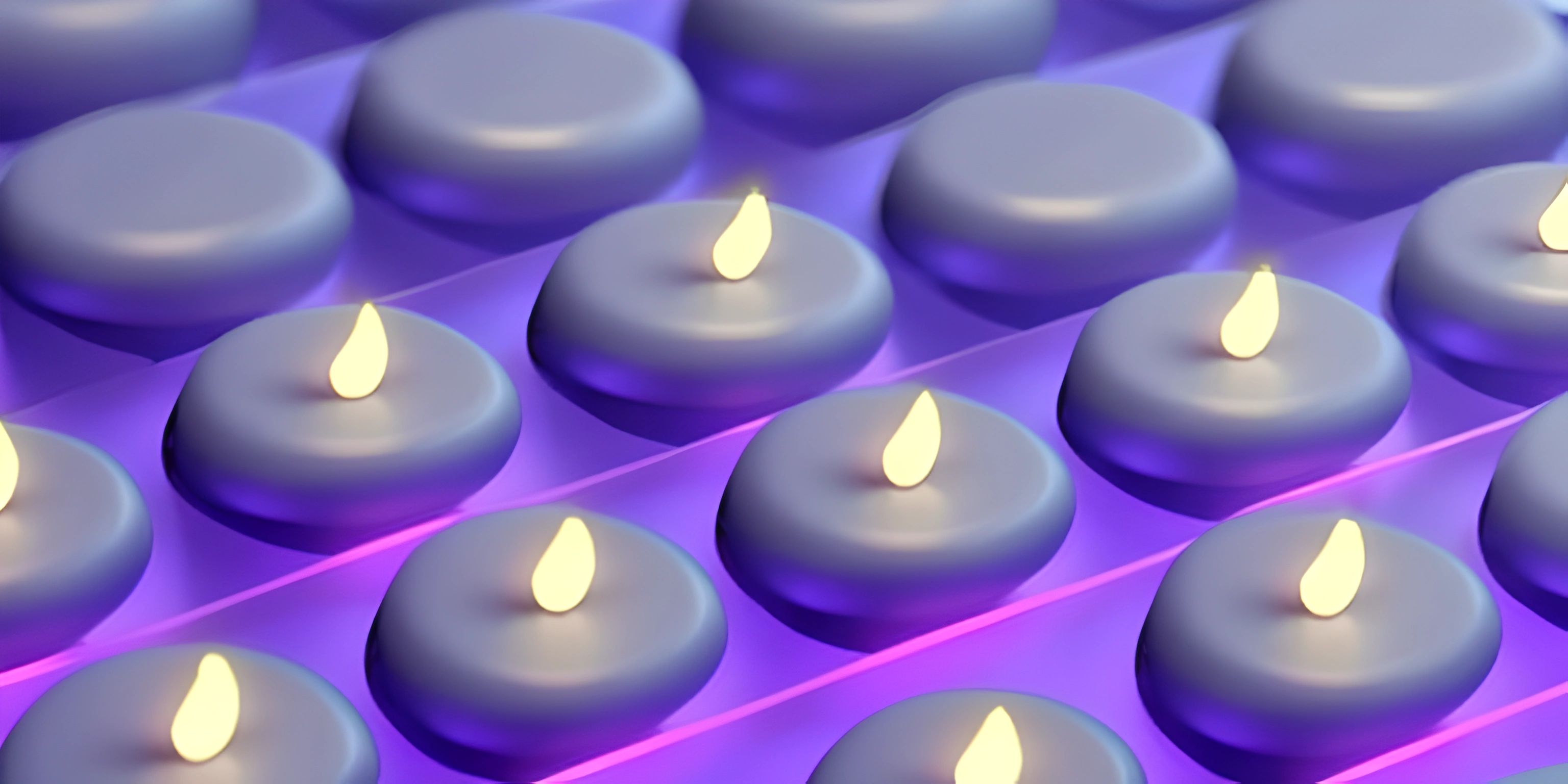 many blue candles are lit kathmanduing on a glass table top in purple light and bright